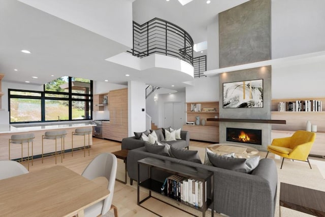 living room with a high ceiling, a large fireplace, and light hardwood / wood-style flooring