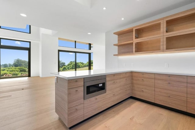 kitchen with stainless steel microwave, kitchen peninsula, and a healthy amount of sunlight