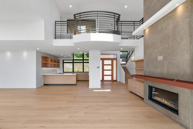 unfurnished living room with a towering ceiling and light hardwood / wood-style flooring