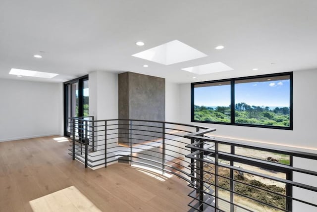 corridor with light hardwood / wood-style flooring, a skylight, and expansive windows