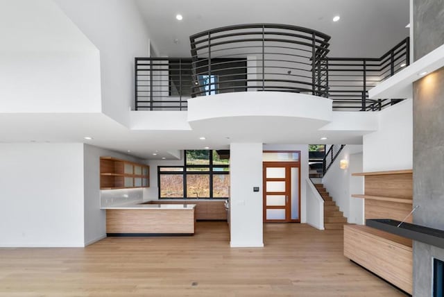 unfurnished living room with a towering ceiling and light hardwood / wood-style flooring