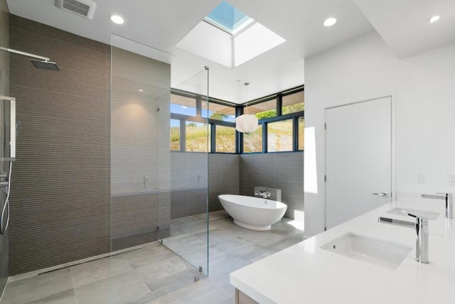 bathroom with vanity, plus walk in shower, a skylight, and tile walls