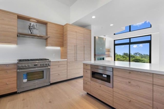 kitchen with high end stainless steel range, exhaust hood, and light wood-type flooring