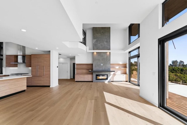 unfurnished living room featuring a large fireplace, light hardwood / wood-style flooring, and a towering ceiling