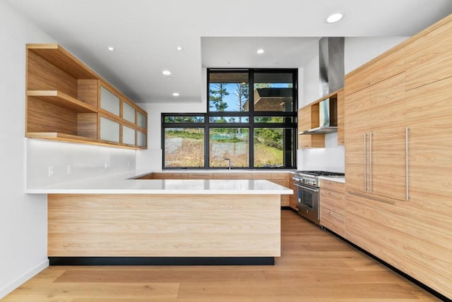 kitchen with stainless steel range, kitchen peninsula, and light hardwood / wood-style flooring