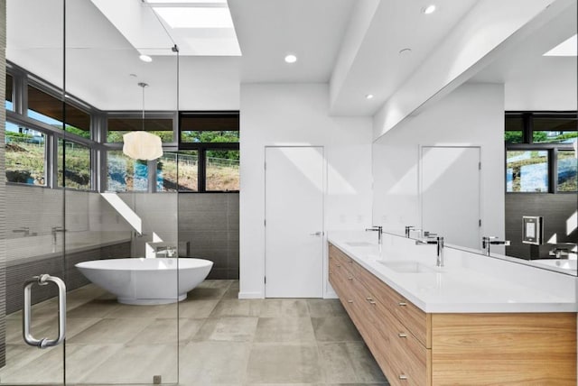 bathroom with vanity, shower with separate bathtub, and a skylight