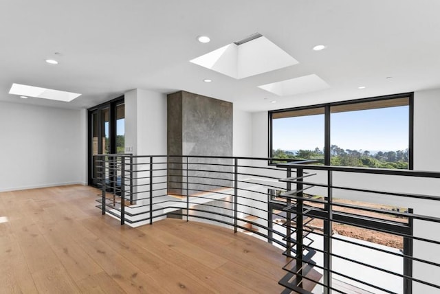 corridor featuring expansive windows, plenty of natural light, a skylight, and light wood-type flooring