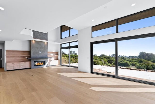 unfurnished living room with a fireplace, light hardwood / wood-style floors, and a high ceiling