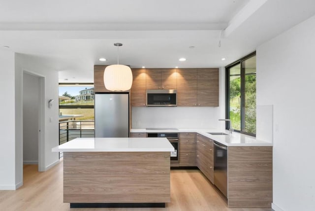 kitchen featuring sink, decorative light fixtures, stainless steel appliances, and light wood-type flooring