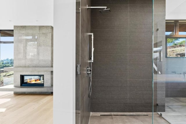 bathroom with a tiled fireplace, hardwood / wood-style flooring, and tiled shower