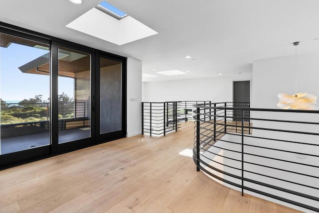 corridor with a skylight, light hardwood / wood-style floors, and a wall of windows