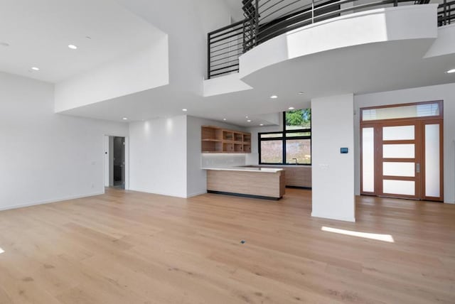 unfurnished living room featuring a high ceiling and light wood-type flooring