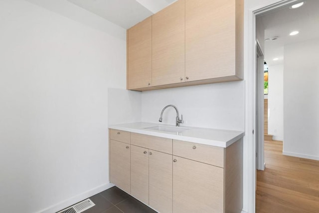 kitchen featuring light brown cabinetry, sink, and dark tile patterned flooring