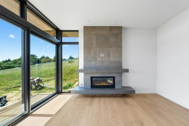 unfurnished living room with a wall of windows, a fireplace, and light wood-type flooring