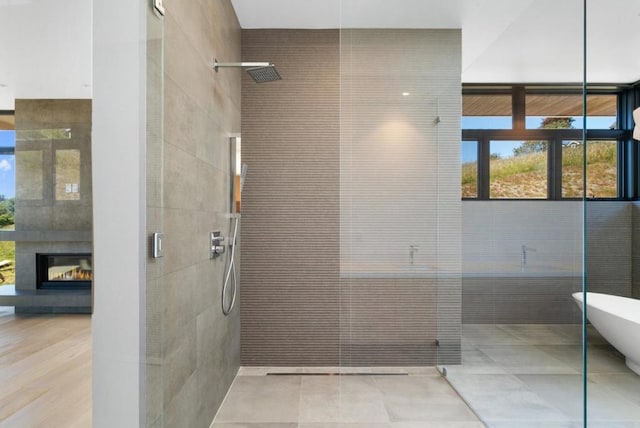 bathroom with tile walls, a fireplace, and separate shower and tub