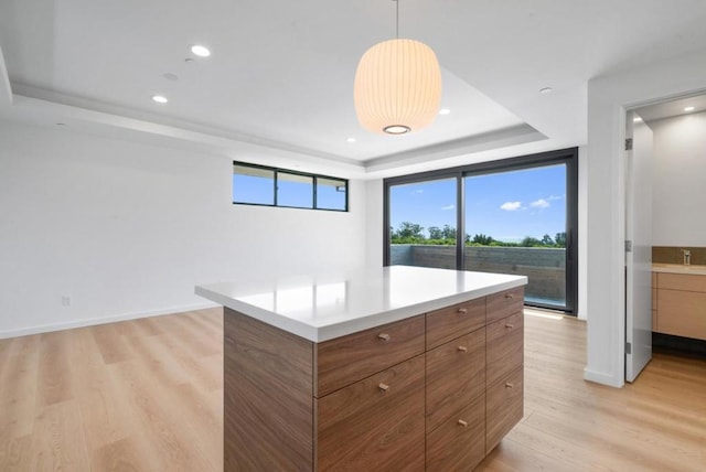 kitchen with a center island, decorative light fixtures, a raised ceiling, and light hardwood / wood-style flooring