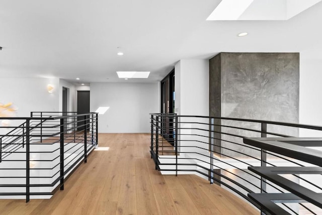 hallway featuring a skylight and light wood-type flooring