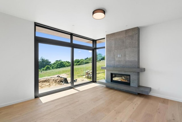 unfurnished living room with expansive windows, a fireplace, and light hardwood / wood-style floors