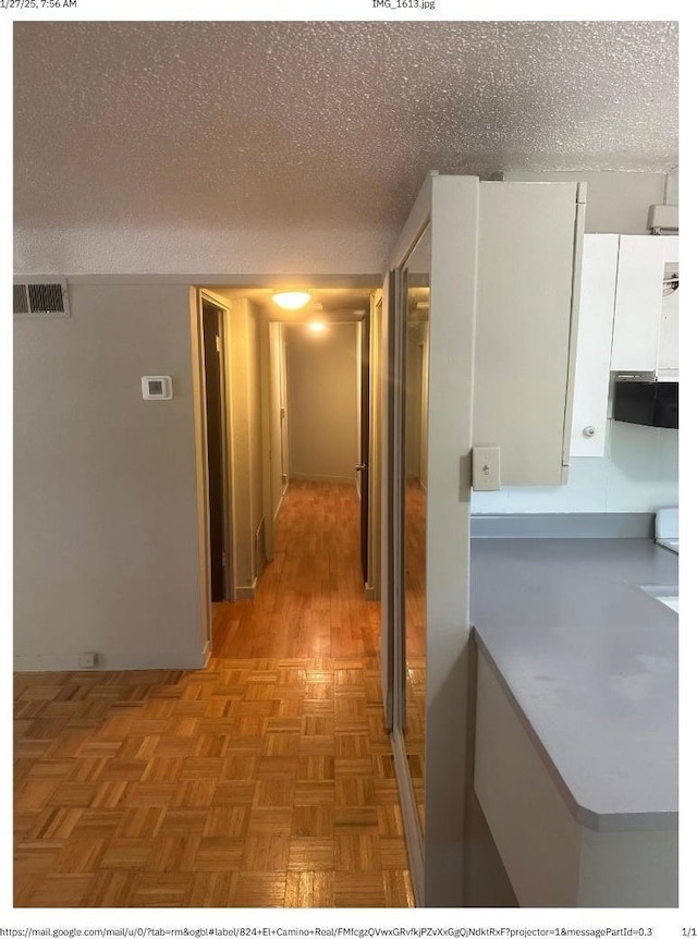 corridor featuring parquet flooring and a textured ceiling