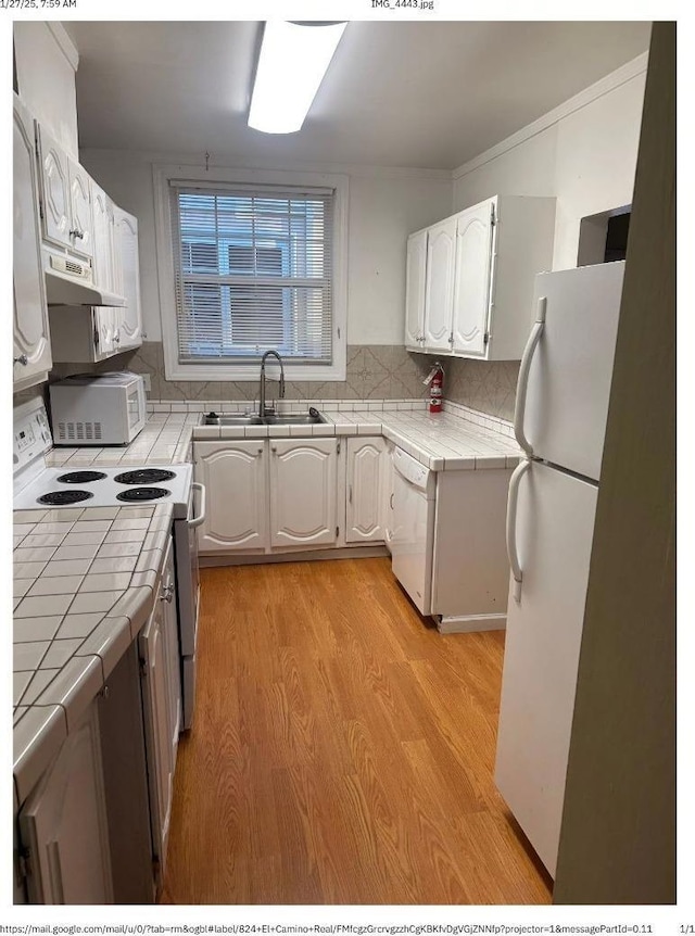 kitchen with sink, tile counters, white cabinets, and white appliances