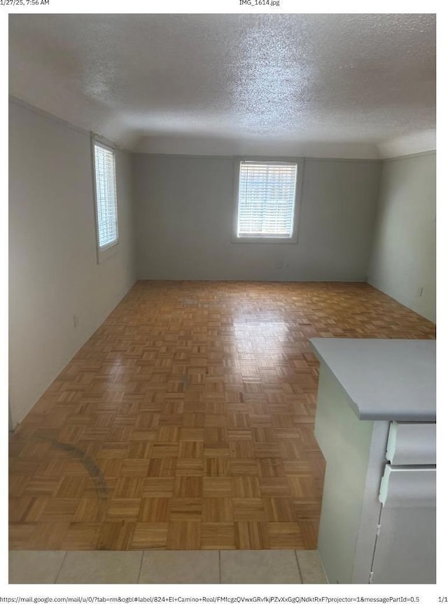 unfurnished room featuring dark parquet flooring and a textured ceiling