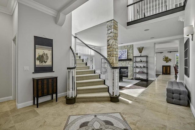 foyer with crown molding, a towering ceiling, a fireplace, and ornate columns