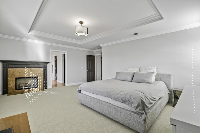 carpeted bedroom featuring ornamental molding, a raised ceiling, and a tile fireplace