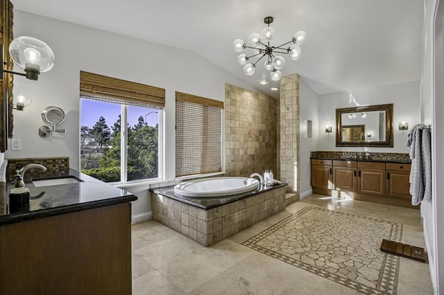 bathroom featuring tiled tub, vanity, lofted ceiling, and a notable chandelier