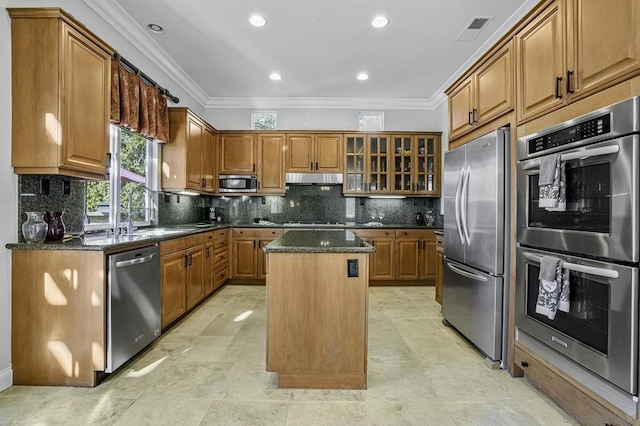 kitchen with appliances with stainless steel finishes, a center island, sink, and dark stone counters