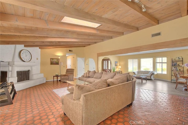 living room with a skylight, wooden ceiling, track lighting, a large fireplace, and beam ceiling