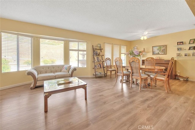 living room featuring ceiling fan, a healthy amount of sunlight, a textured ceiling, and light hardwood / wood-style floors