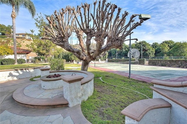 view of property's community featuring a yard and tennis court