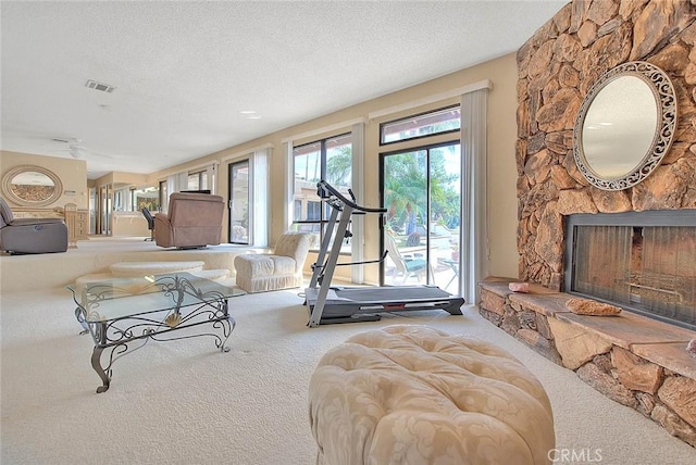 living room featuring a stone fireplace, carpet floors, and a textured ceiling