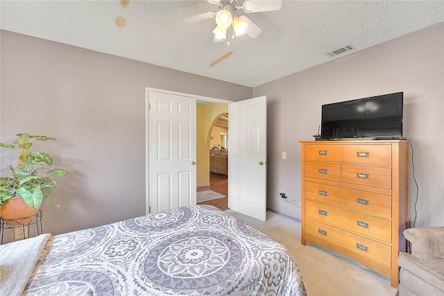 carpeted bedroom featuring ceiling fan and a textured ceiling