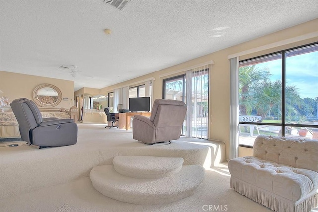 carpeted living room featuring ceiling fan and a textured ceiling