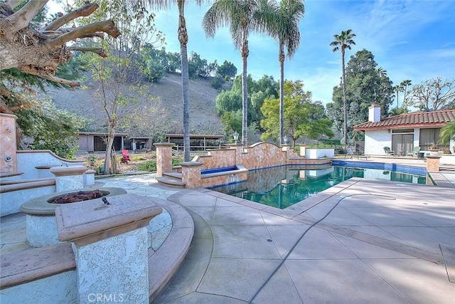 view of pool with an outdoor fire pit and a patio area