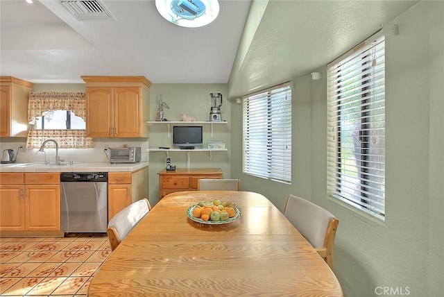 kitchen featuring sink, light tile patterned floors, dishwasher, tile countertops, and light brown cabinets