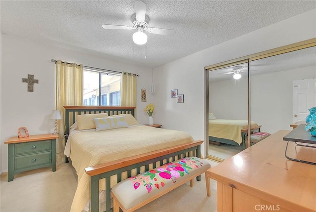 carpeted bedroom featuring ceiling fan, a closet, and a textured ceiling