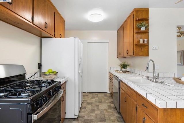 kitchen featuring tile countertops, black gas stove, sink, and dishwasher