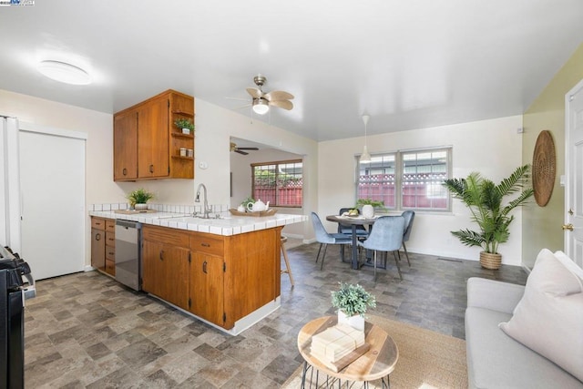 kitchen with sink, a kitchen breakfast bar, tile countertops, stainless steel dishwasher, and kitchen peninsula