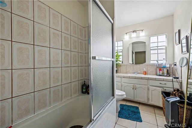 full bathroom with tile patterned floors, toilet, combined bath / shower with glass door, vanity, and backsplash