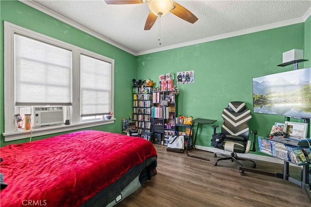 bedroom featuring wood-type flooring, cooling unit, ornamental molding, ceiling fan, and a textured ceiling