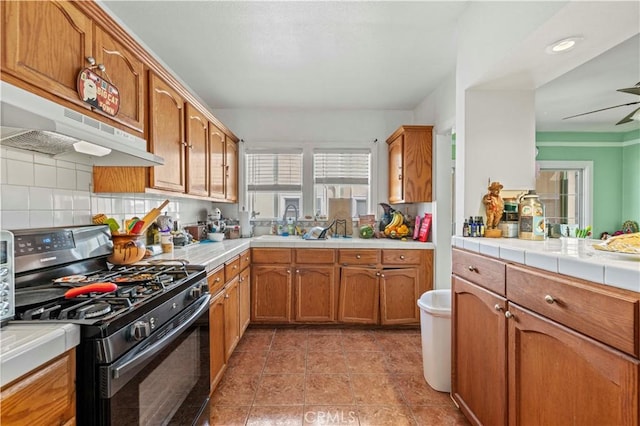 kitchen featuring tasteful backsplash, tile counters, gas range oven, and light tile patterned floors