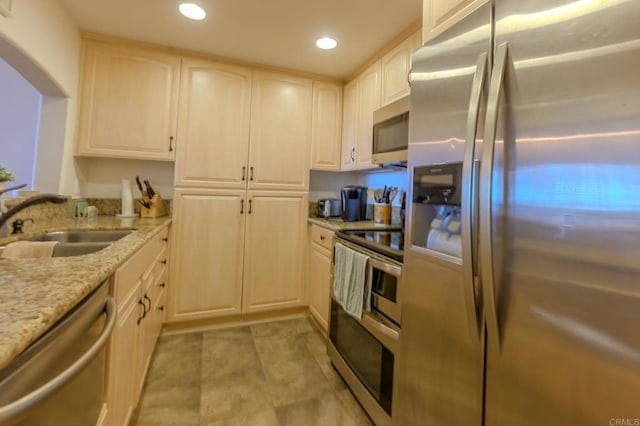 kitchen with arched walkways, appliances with stainless steel finishes, light stone counters, a sink, and recessed lighting