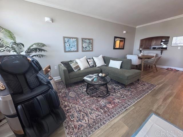 living area with ornamental molding, wood finished floors, and baseboards