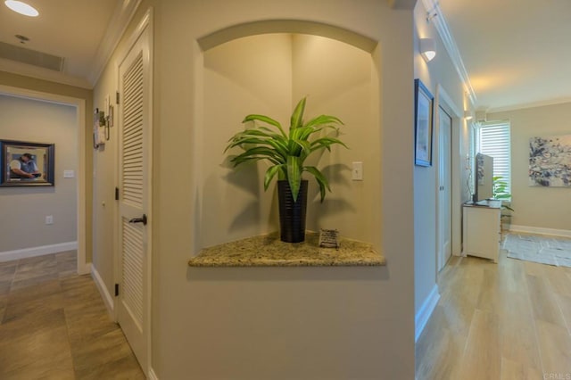 hall featuring light wood-type flooring, baseboards, and ornamental molding