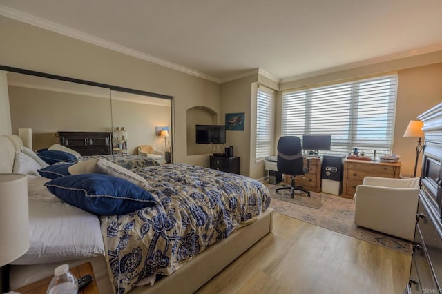 bedroom with light wood-style flooring, a fireplace, and crown molding