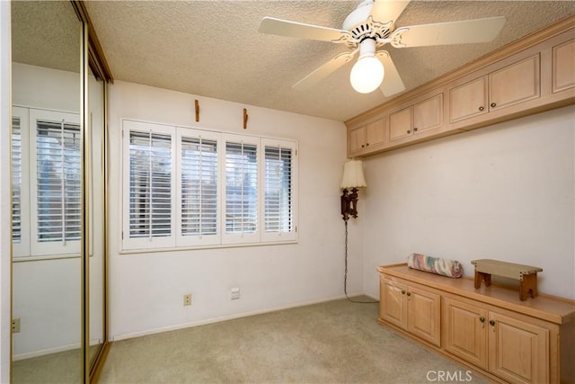 interior space featuring light carpet, a textured ceiling, and ceiling fan