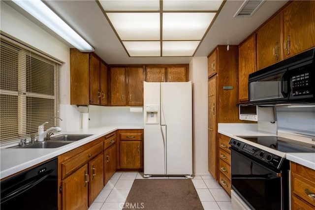 kitchen with sink, light tile patterned floors, and black appliances