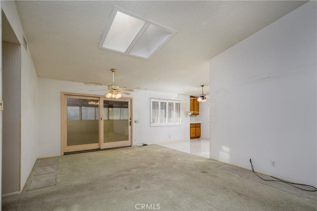 unfurnished living room featuring light carpet, a textured ceiling, ceiling fan, and a skylight